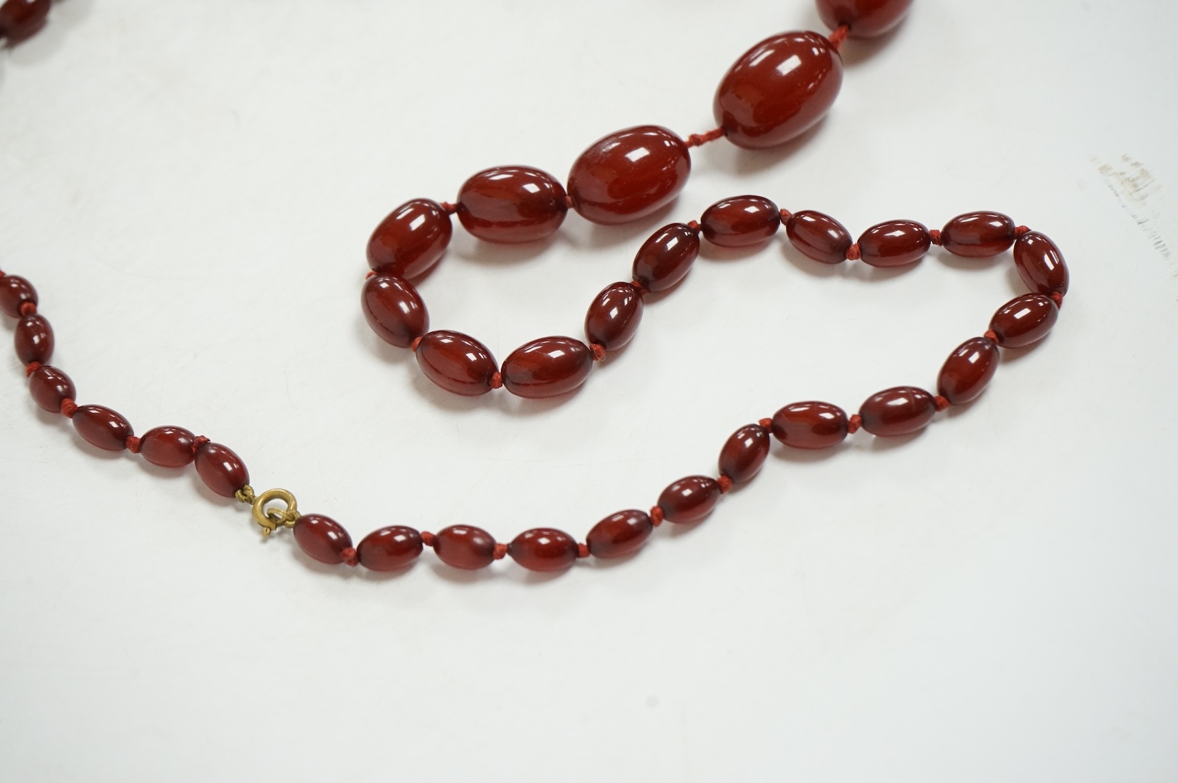 A single strand graduated simulated oval cherry amber bead necklace, string broken, gross weight 73 grams.